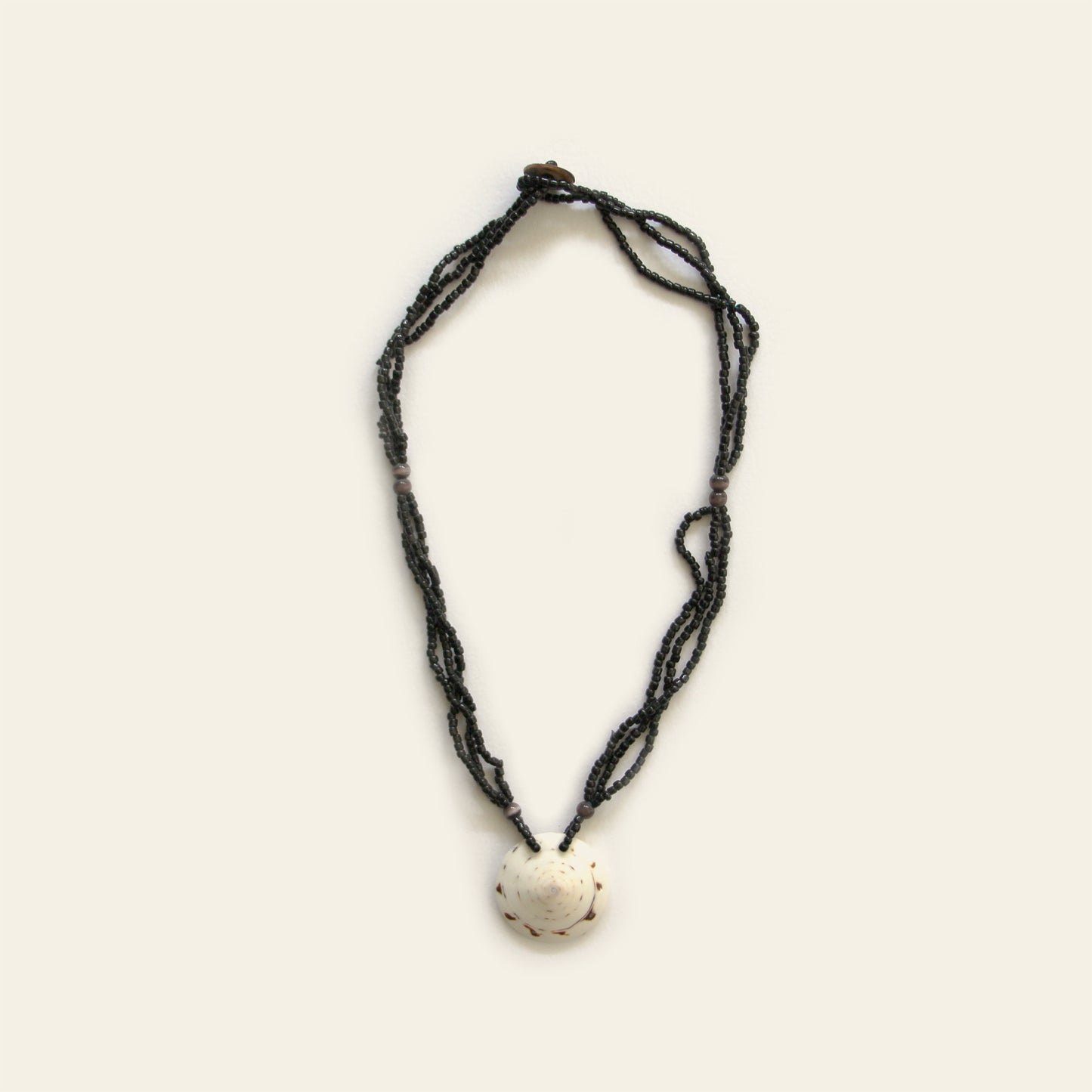Handmade necklace with layered black seed beads and a white natural shell pendant — Nayabijou.