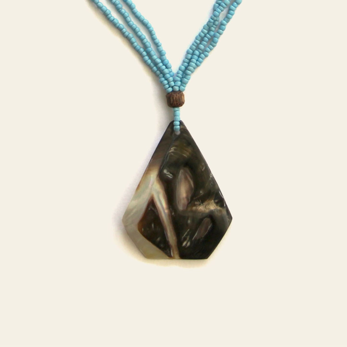 Closeup of handmade necklace with triangular mother of pearl shell pendant and beaded strands – Nayabijou.