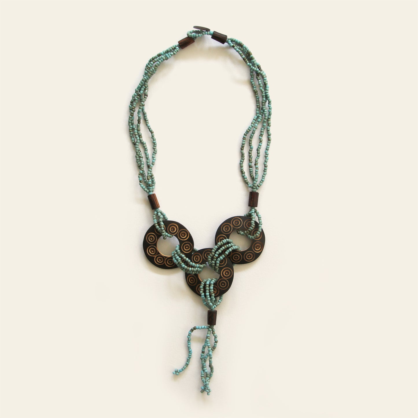 Handmade necklace featuring Sand seed beads and carved coconut shell loops linked together with beaded knots, finished with a tasseled drop β by Nayabijou.
