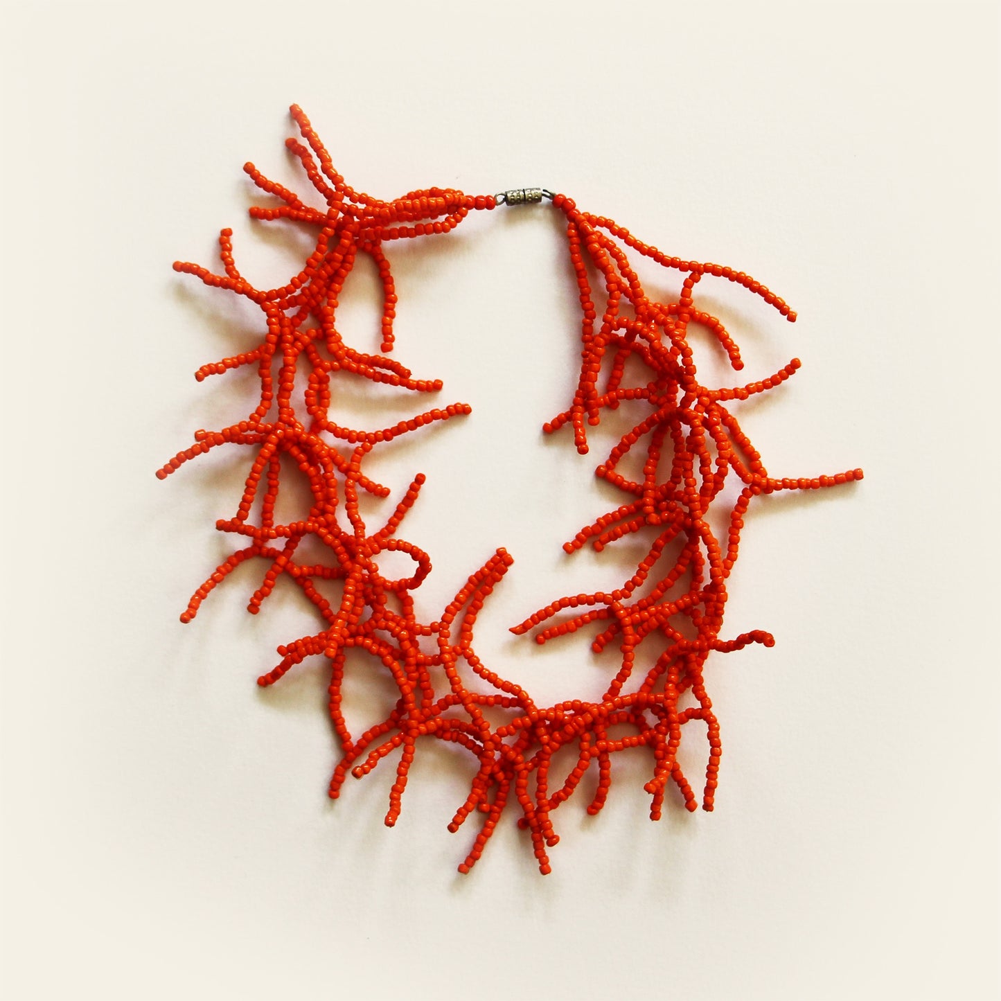 Handcrafted necklace with red coral-like bead branches arranged in a circular design