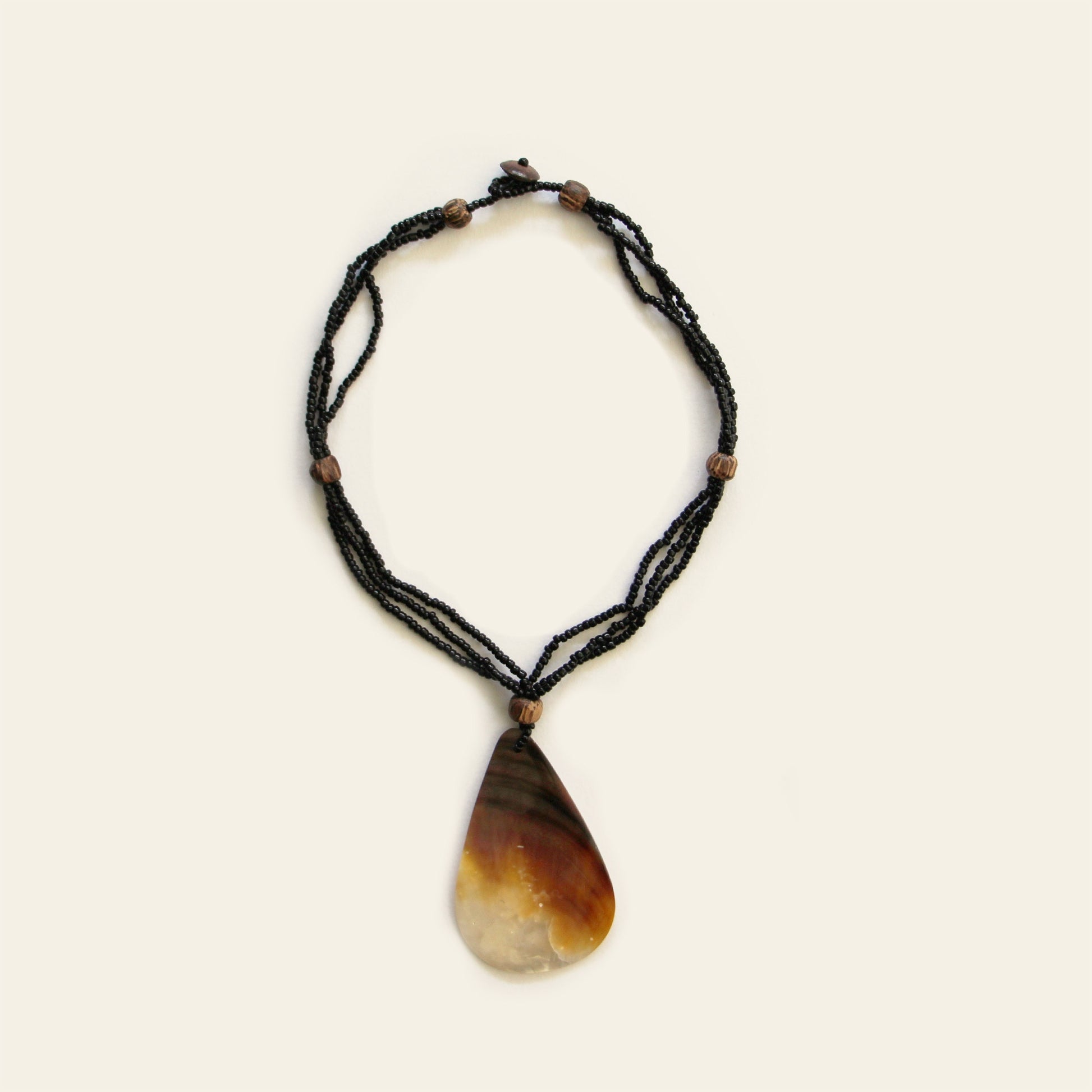 Full view of teardrop-shaped mother-of-pearl pendant necklace with black seed beads and wooden accents – Nayabijou.