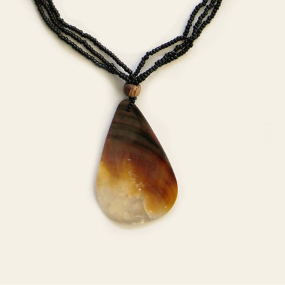 Close-up of teardrop mother-of-pearl pendant with black seed beads and wood accent – Nayabijou.