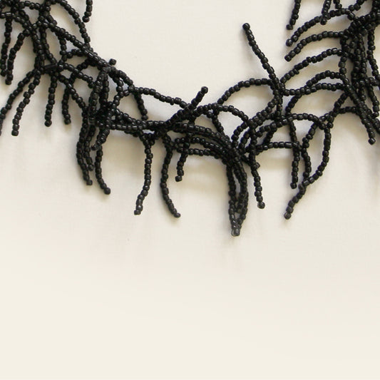 Close-up of black seed beads forming coral-like fringe design