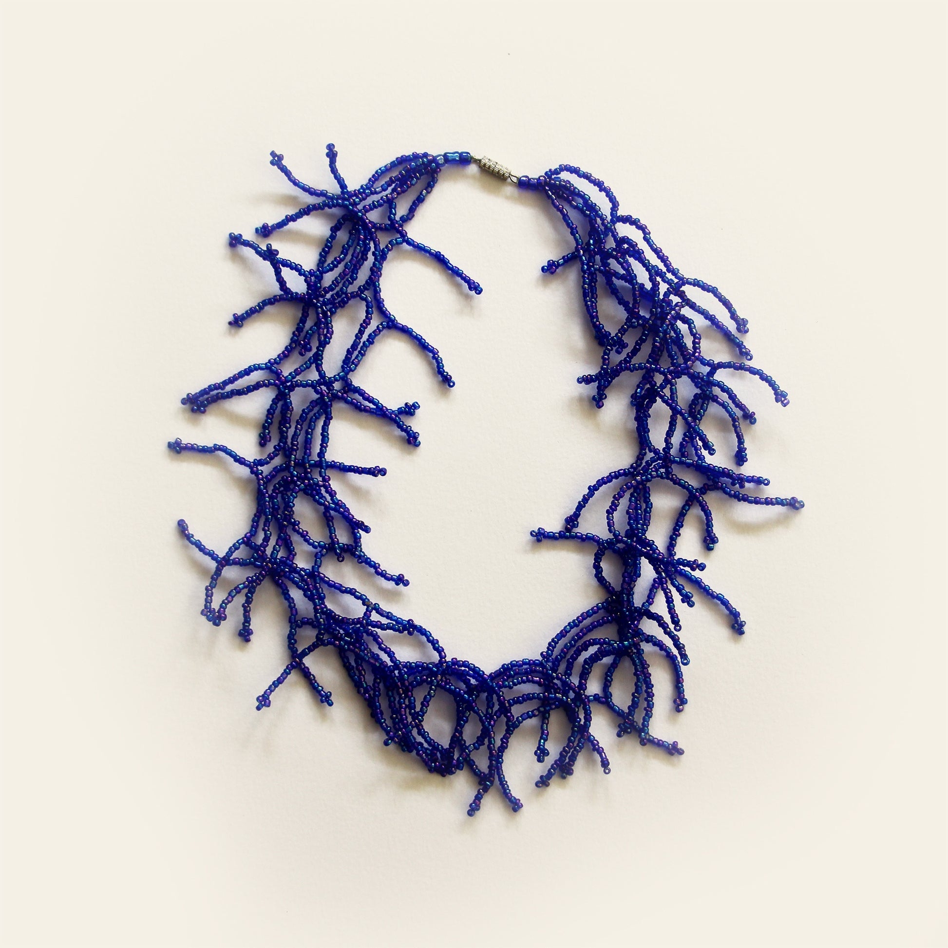 Blue beaded coral-style necklace laid flat on light background