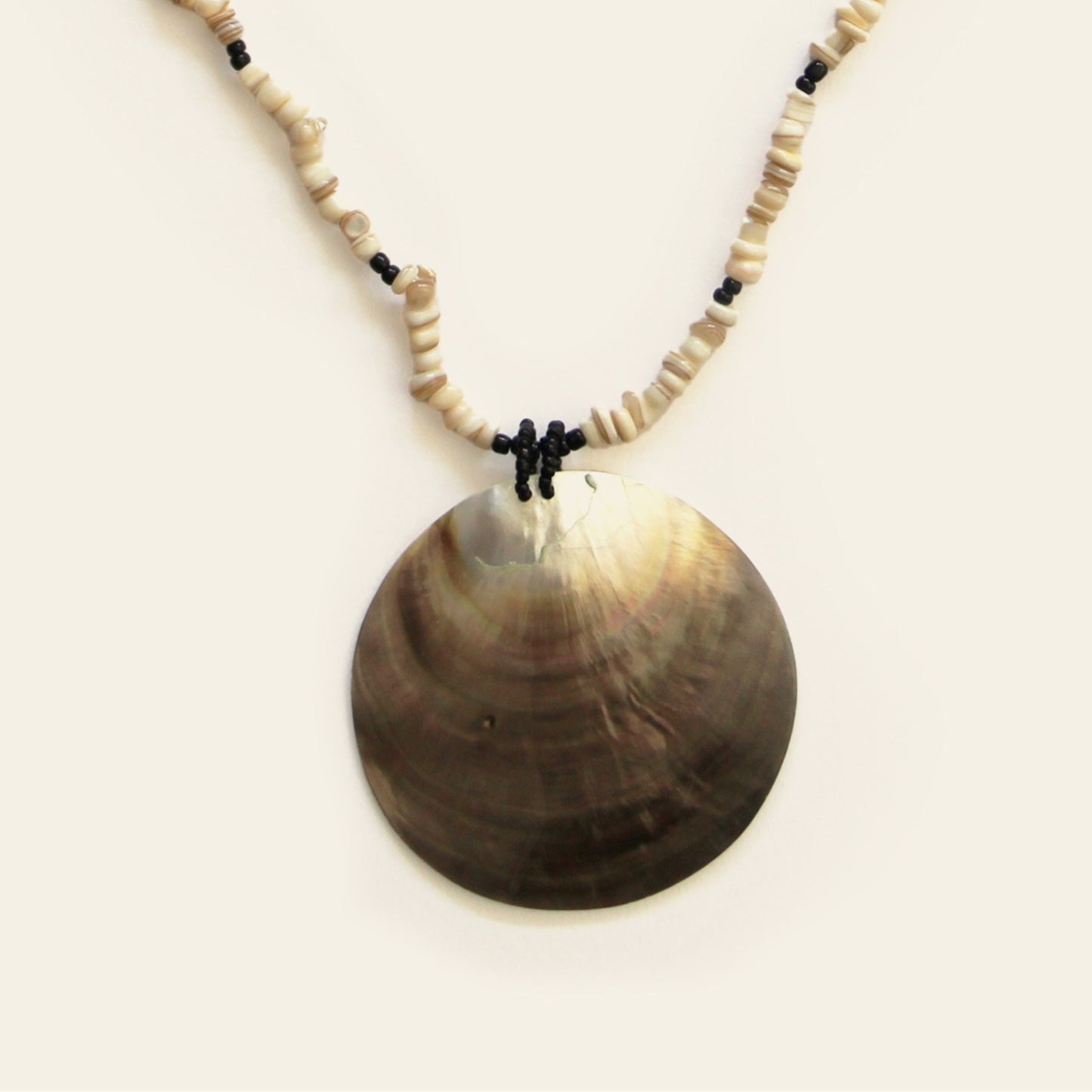 Closeup of mother of pearl pendant necklace with stacked beige and black beads – Nayabijou.