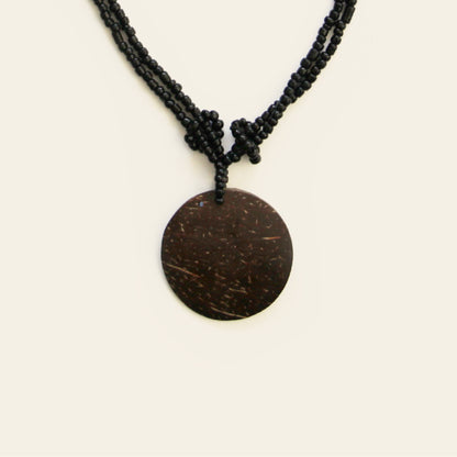 Close-up of coconut pendant with knotted black seed bead strands