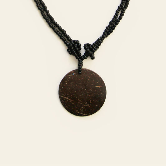 Close-up of coconut pendant with knotted black seed bead strands