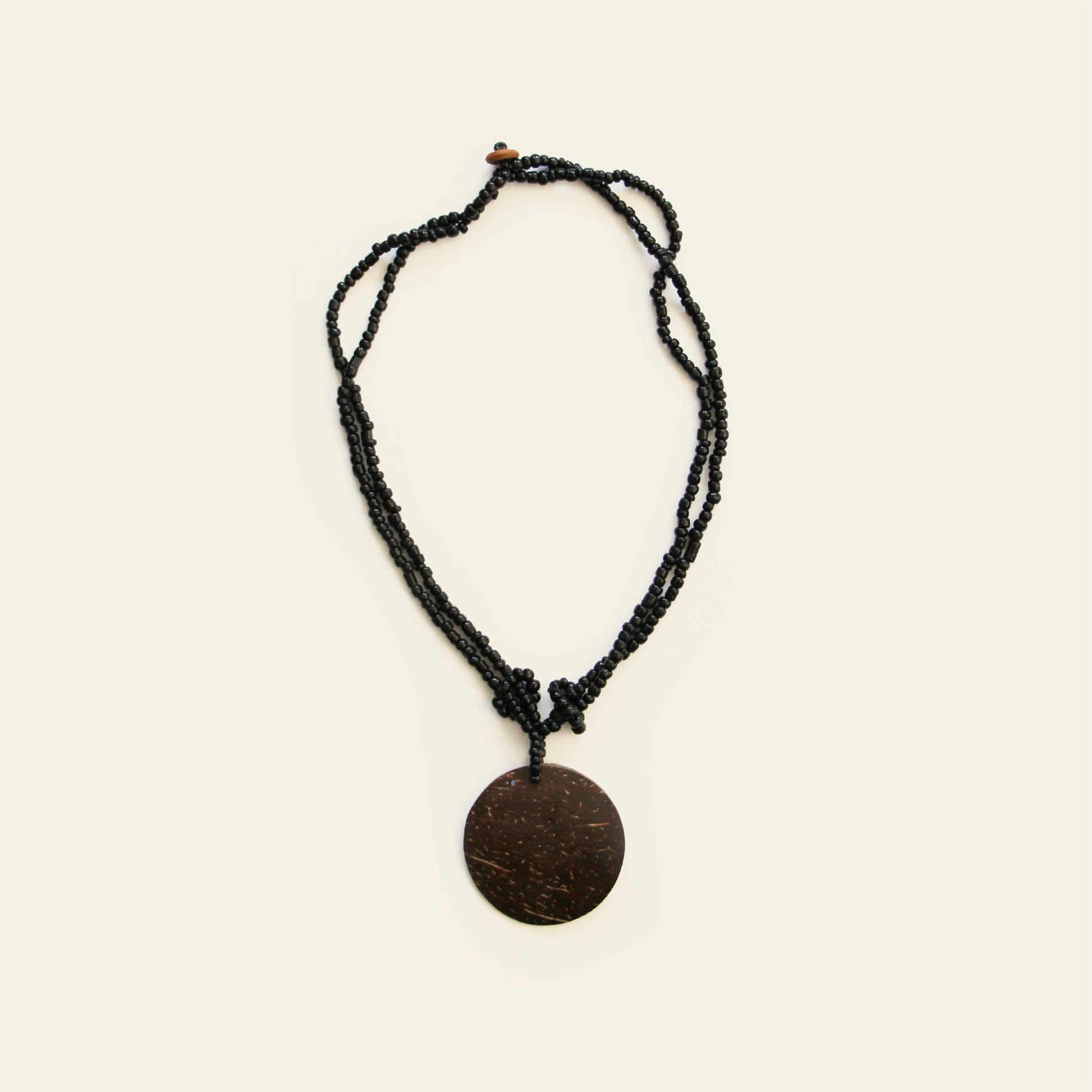 Handmade necklace with coconut shell pendant and black seed beads