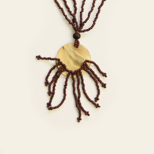 Close-up of golden mother-of-pearl pendant with brown bead fringe.