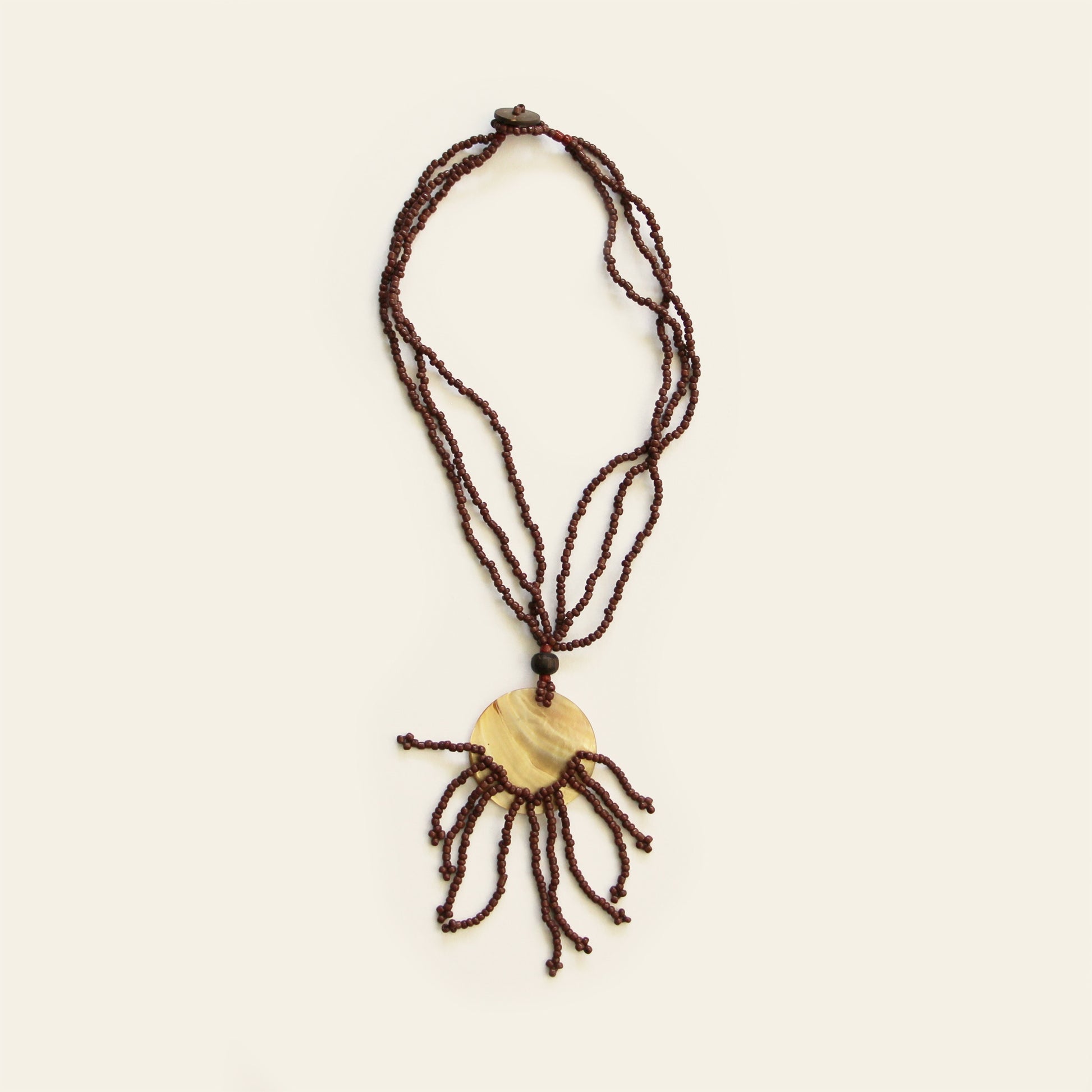 Golden mother-of-pearl necklace with fan-shaped brown beaded fringe on light background