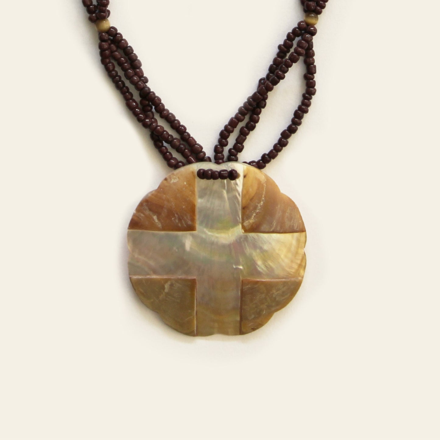 Closeup of warm-toned mother of pearl pendant necklace with dark brown seed bead strands – Nayabijou