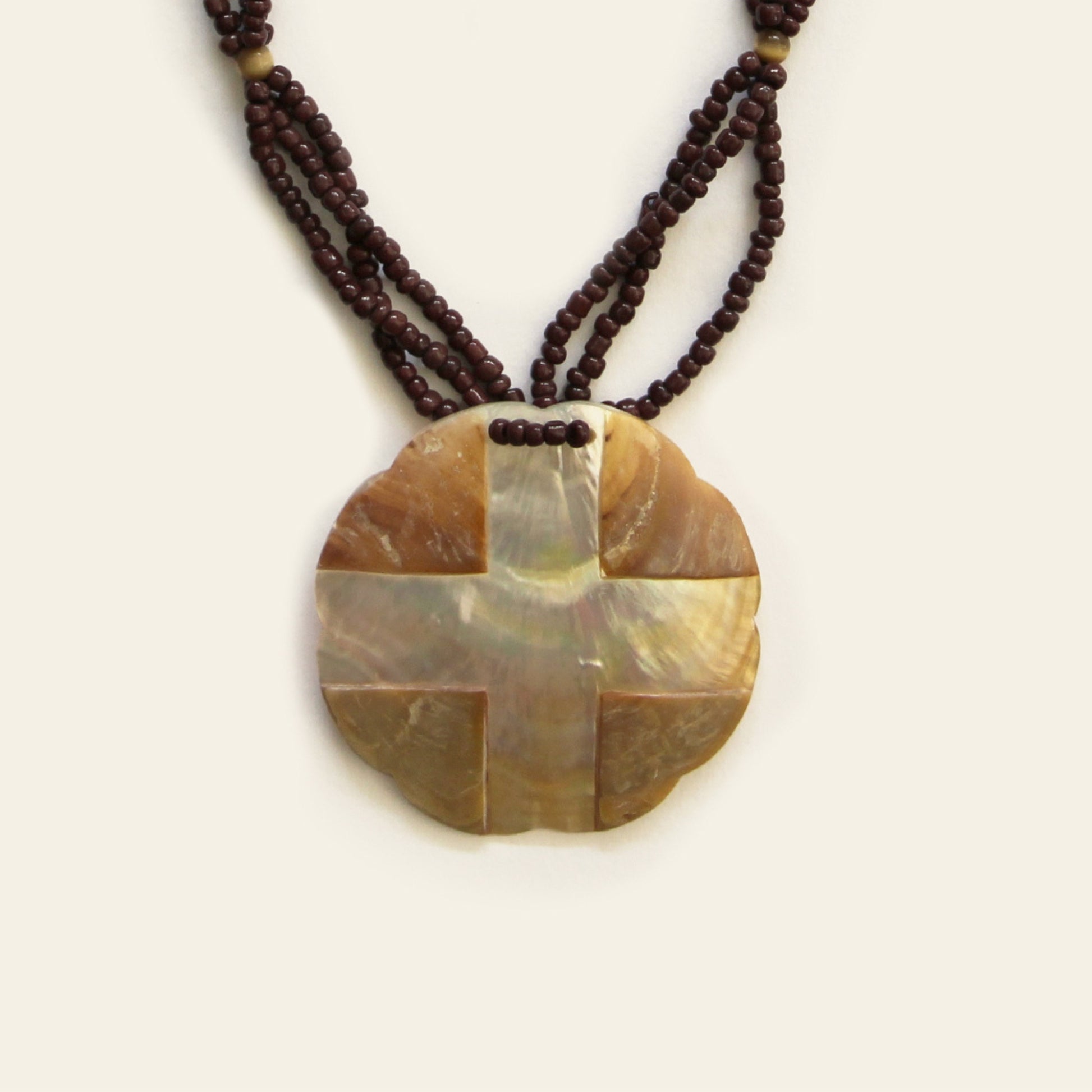 Closeup of warm-toned mother of pearl pendant necklace with dark brown seed bead strands – Nayabijou