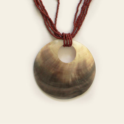 Close-up of mother-of-pearl pendant with red seed beads from Nayabijou