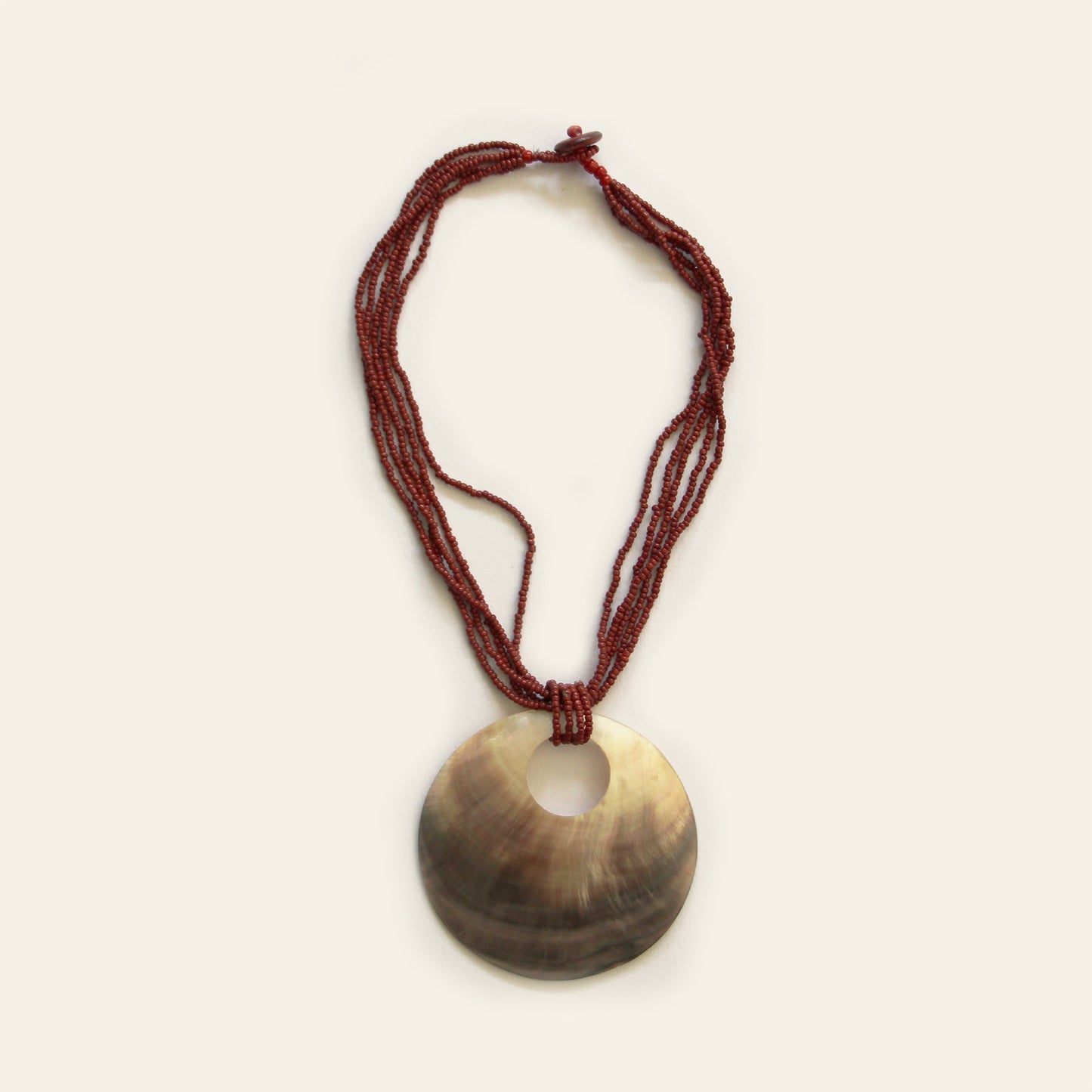 Handmade necklace with mother-of-pearl disc and red beaded strands by Nayabijou