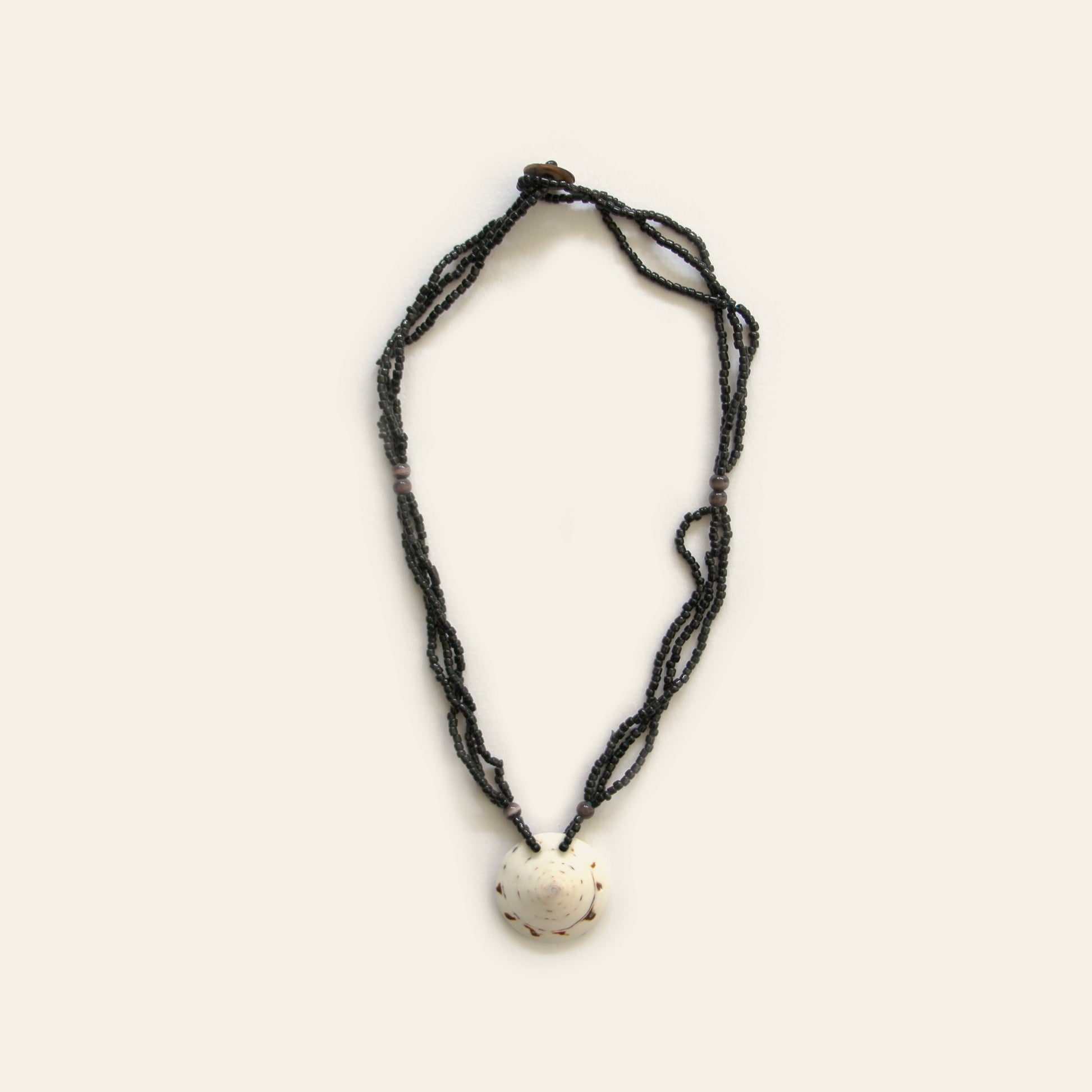 Handmade necklace with layered black seed beads and a white natural shell pendant — Nayabijou.
