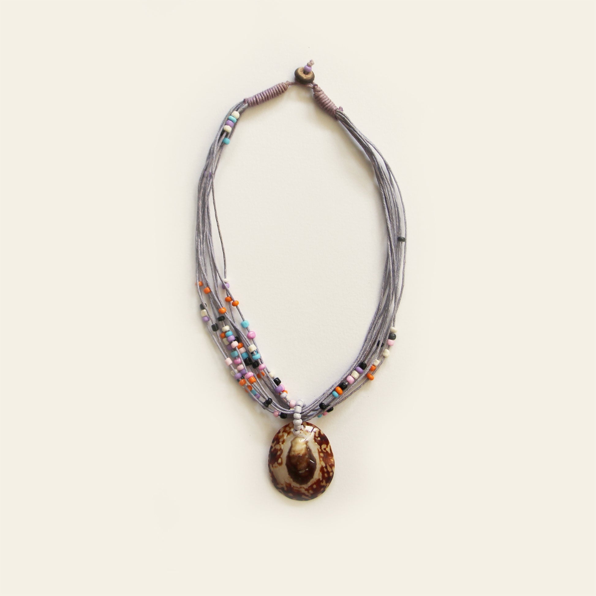 Handmade necklace with gray threads, multicolor beads, and a brown shell pendant — crafted by Nayabijou.