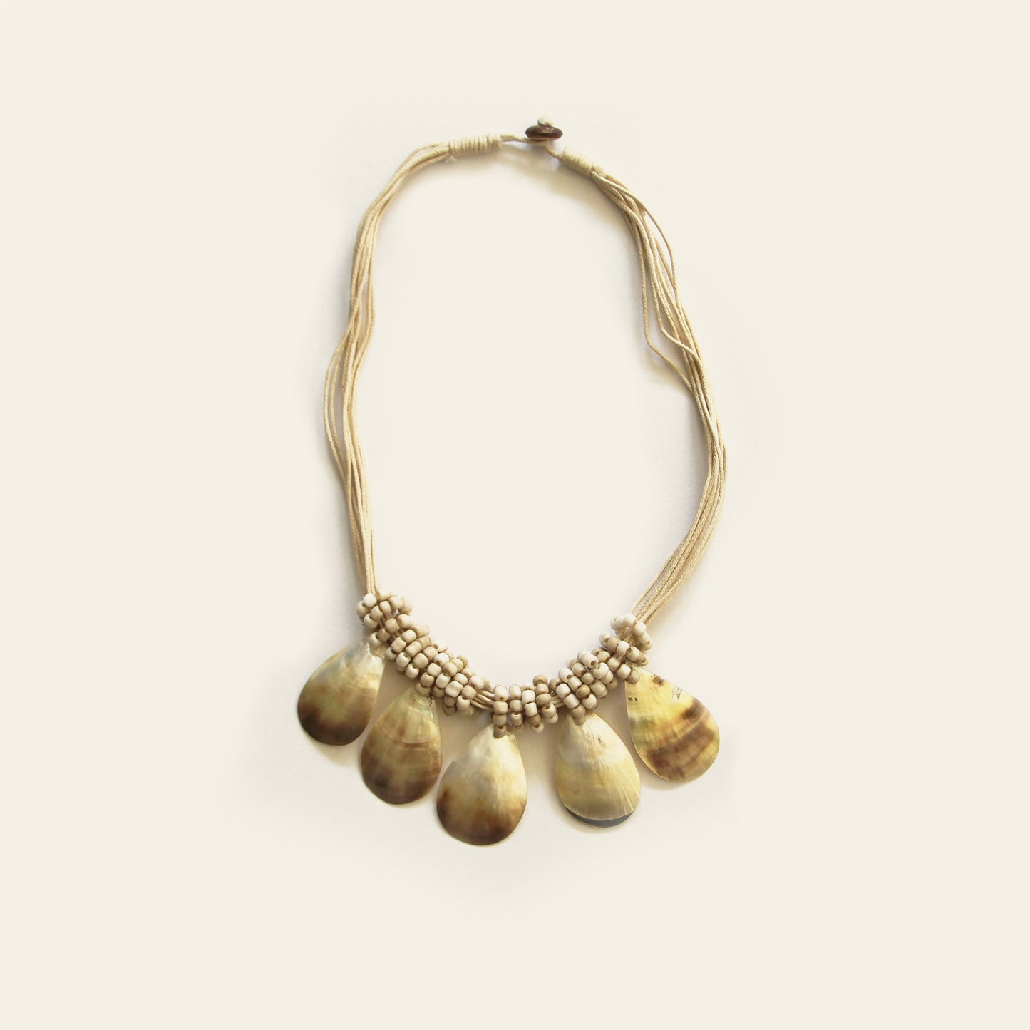 Natural sand-colored teardrop shell necklace with layered black cord and artisanal accents- Nayabijou