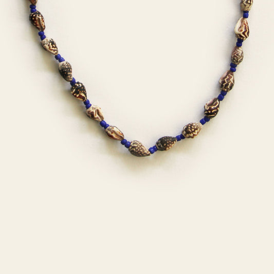Handmade necklace with carved brown beads, small shell accents, and deep blue seed beads — by Nayabijou.