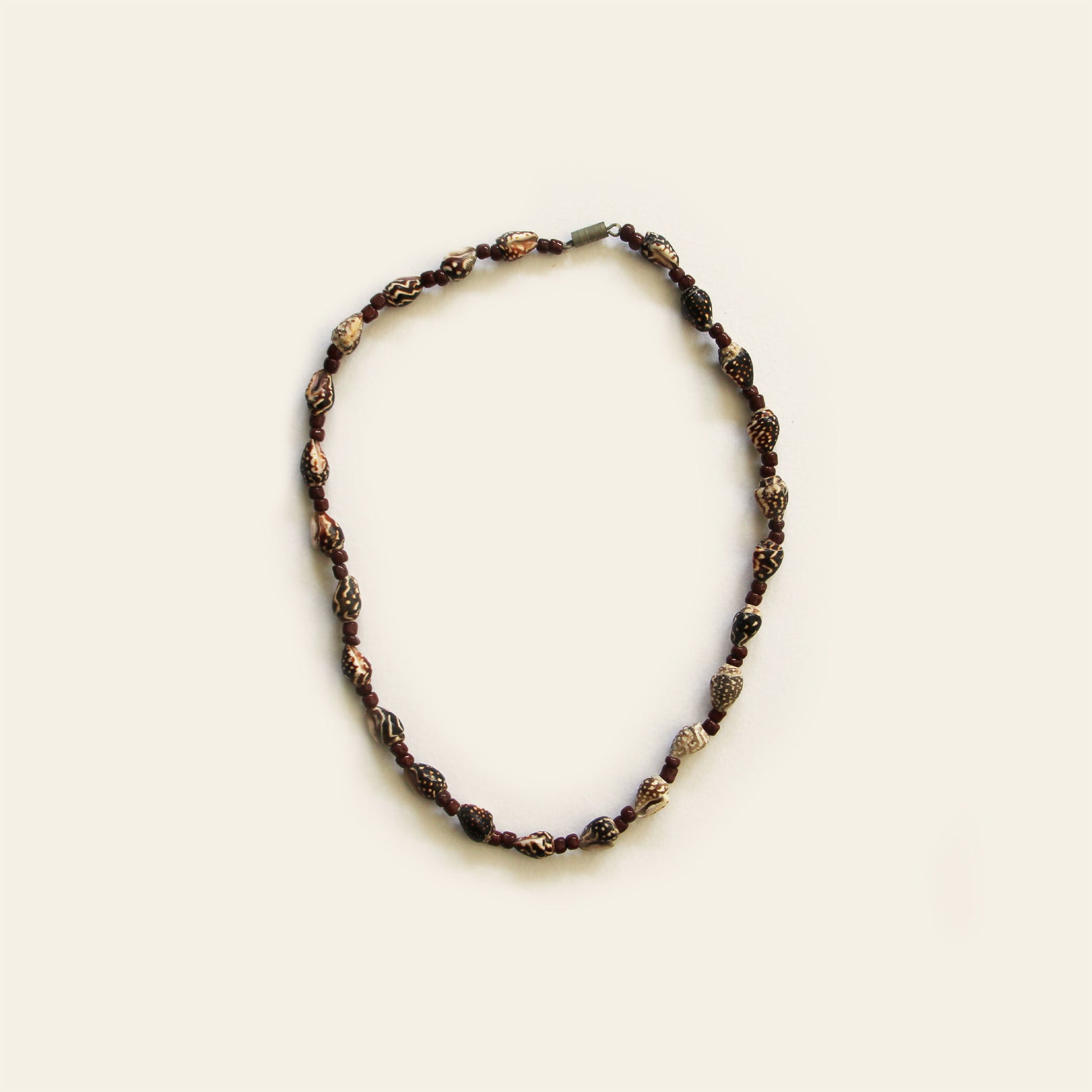 Handmade necklace with carved brown beads, small shell accents, and warm brown seed beads — by Nayabijou.