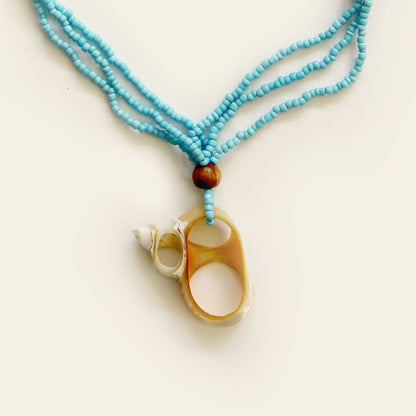 closeup of handmade necklace with Turquoise seed beads, wooden accents, and a natural oval shell pendant with mini shell charms — by Nayabijou.