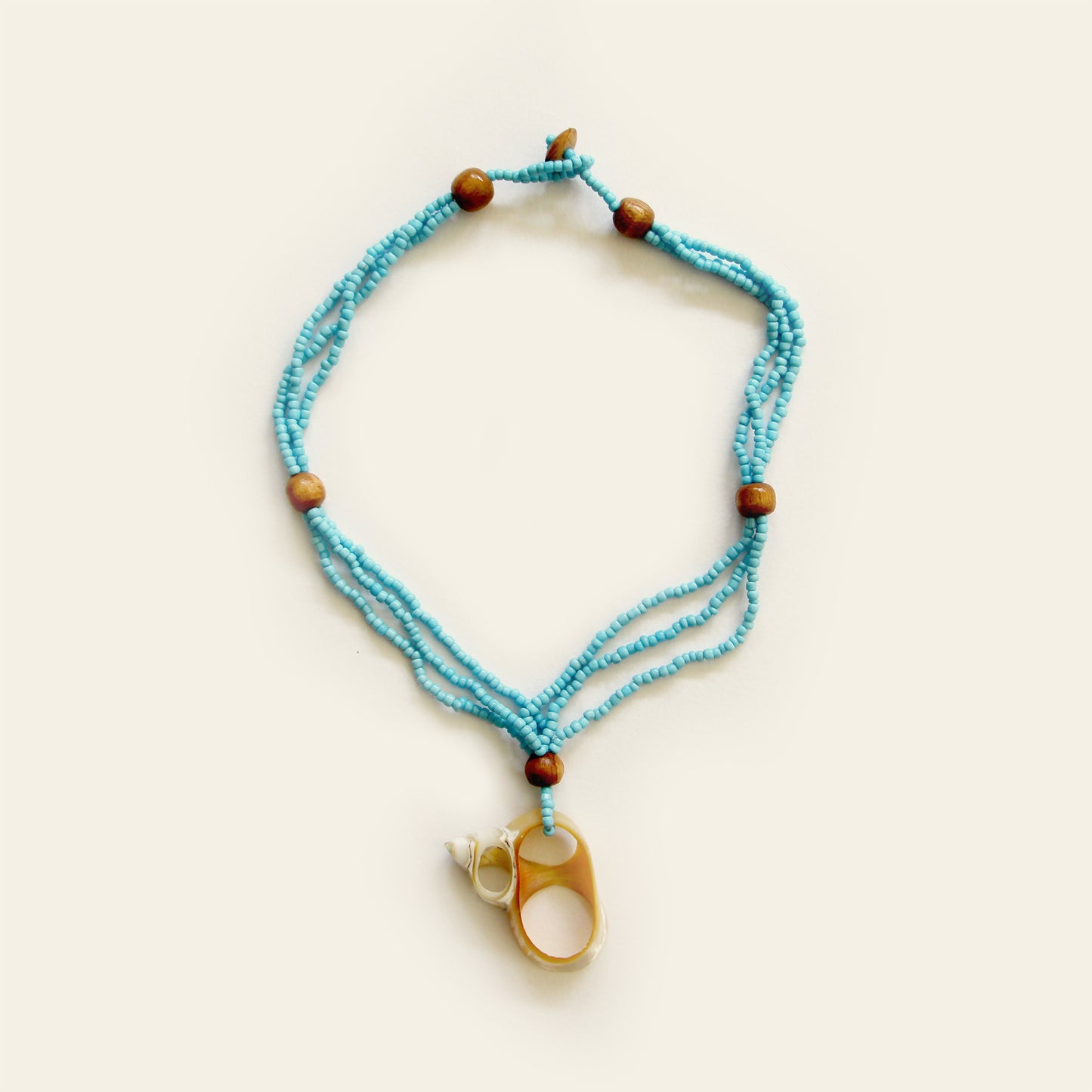 Handmade necklace with Turquoise seed beads, wooden accents, and a natural oval shell pendant with mini shell charms — by Nayabijou.