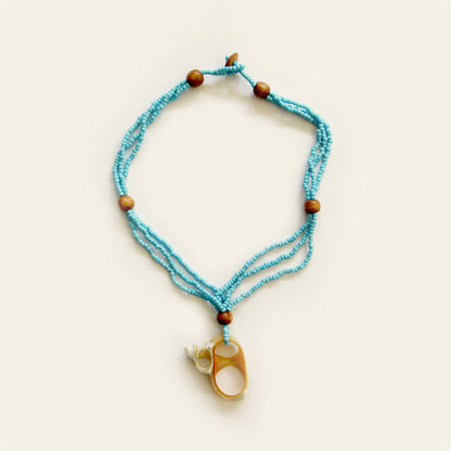 Handmade necklace with Turquoise seed beads, wooden accents, and a natural oval shell pendant with mini shell charms — by Nayabijou.