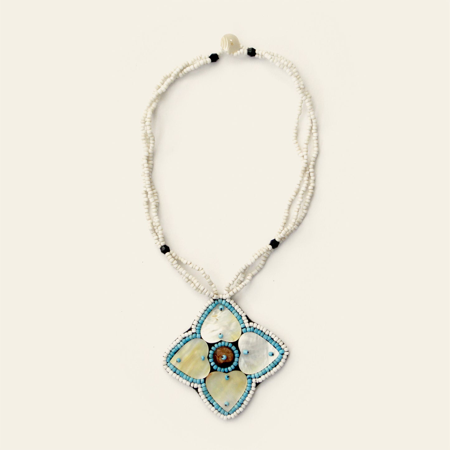 Handmade white beaded necklace featuring a large mother-of-pearl flower pendant with blue accents and central shell detail – Nayabijou.