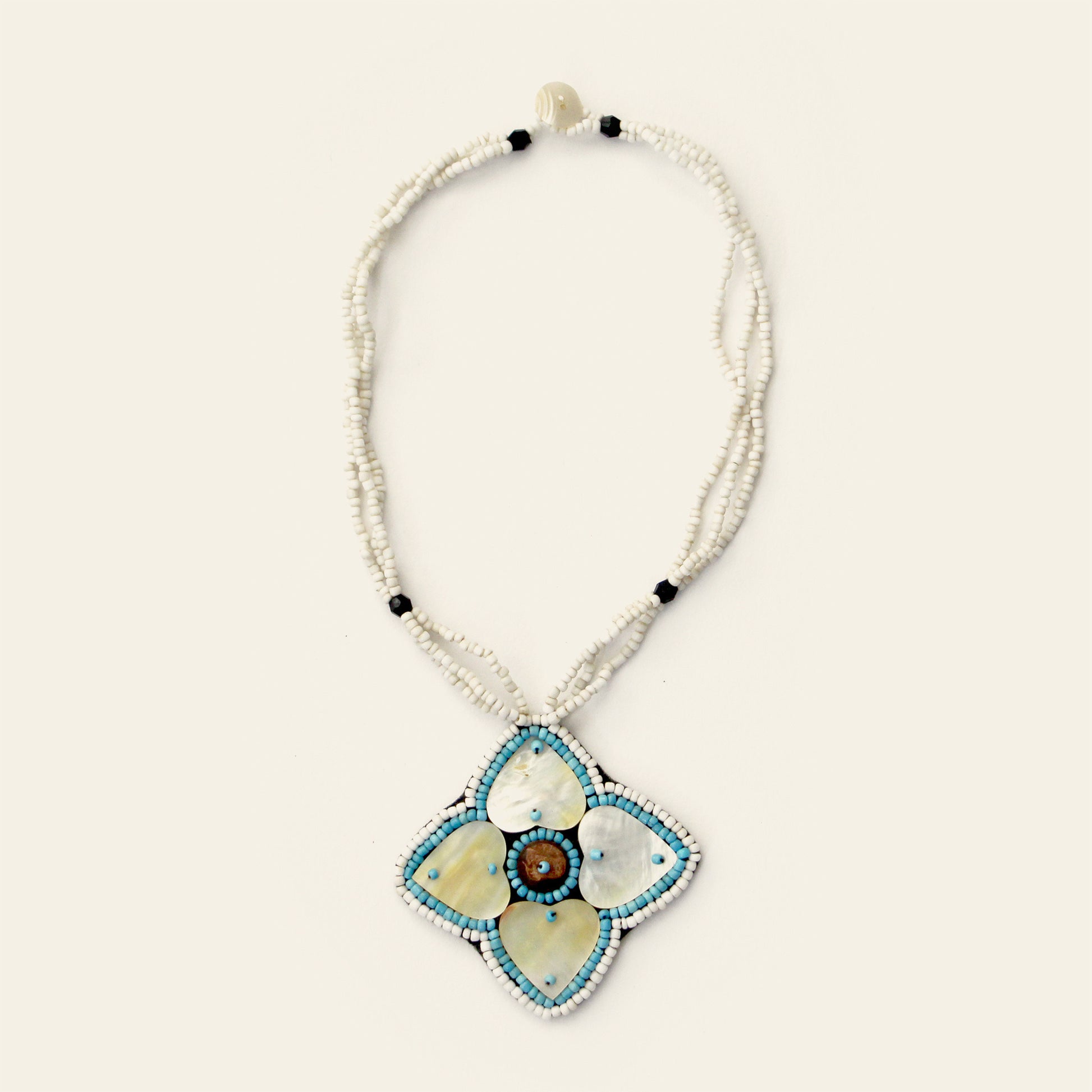 Handmade white beaded necklace featuring a large mother-of-pearl flower pendant with blue accents and central shell detail – Nayabijou.