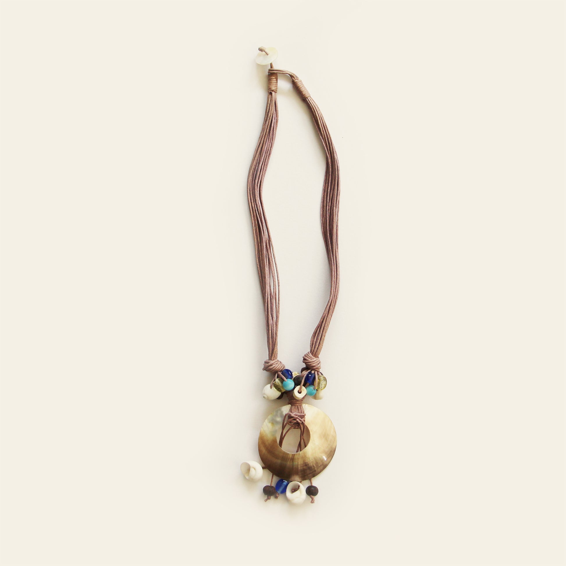 Handmade necklace with taupe cords, a round shell pendant, and a cluster of natural beads – by Nayabijou.