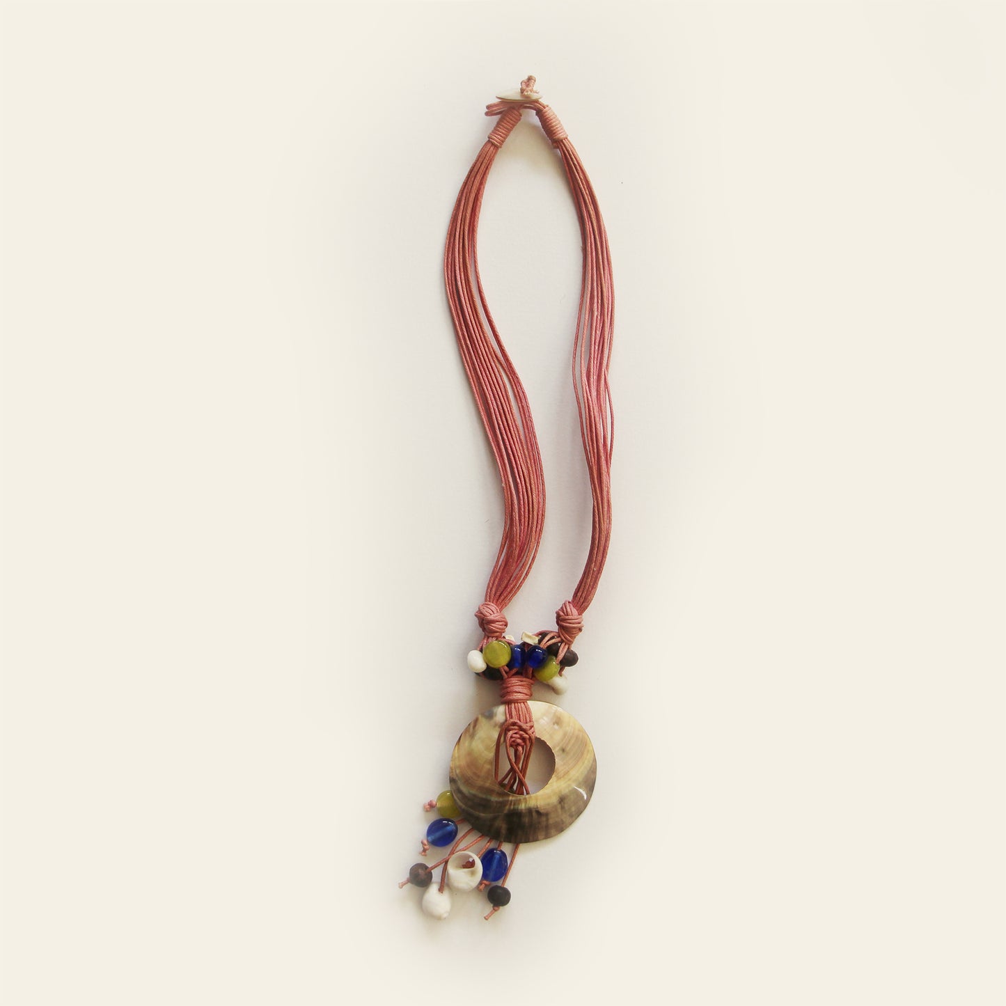 Handmade necklace with mauve cords, a round shell pendant, and colorful natural beads – by Nayabijou.