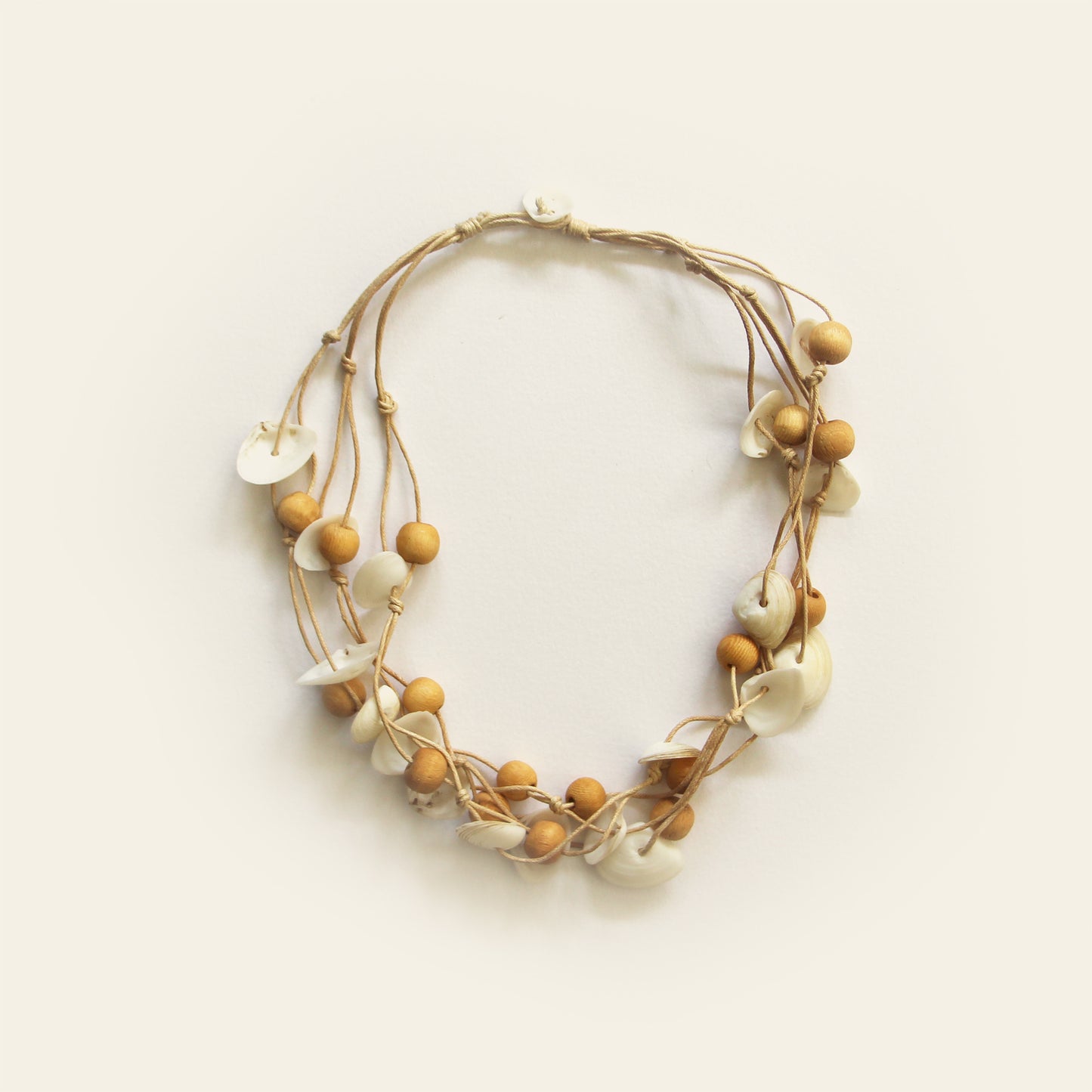 Handmade sand-toned necklace with natural white shell chips and light wooden beads on layered threads — Nayabijou.