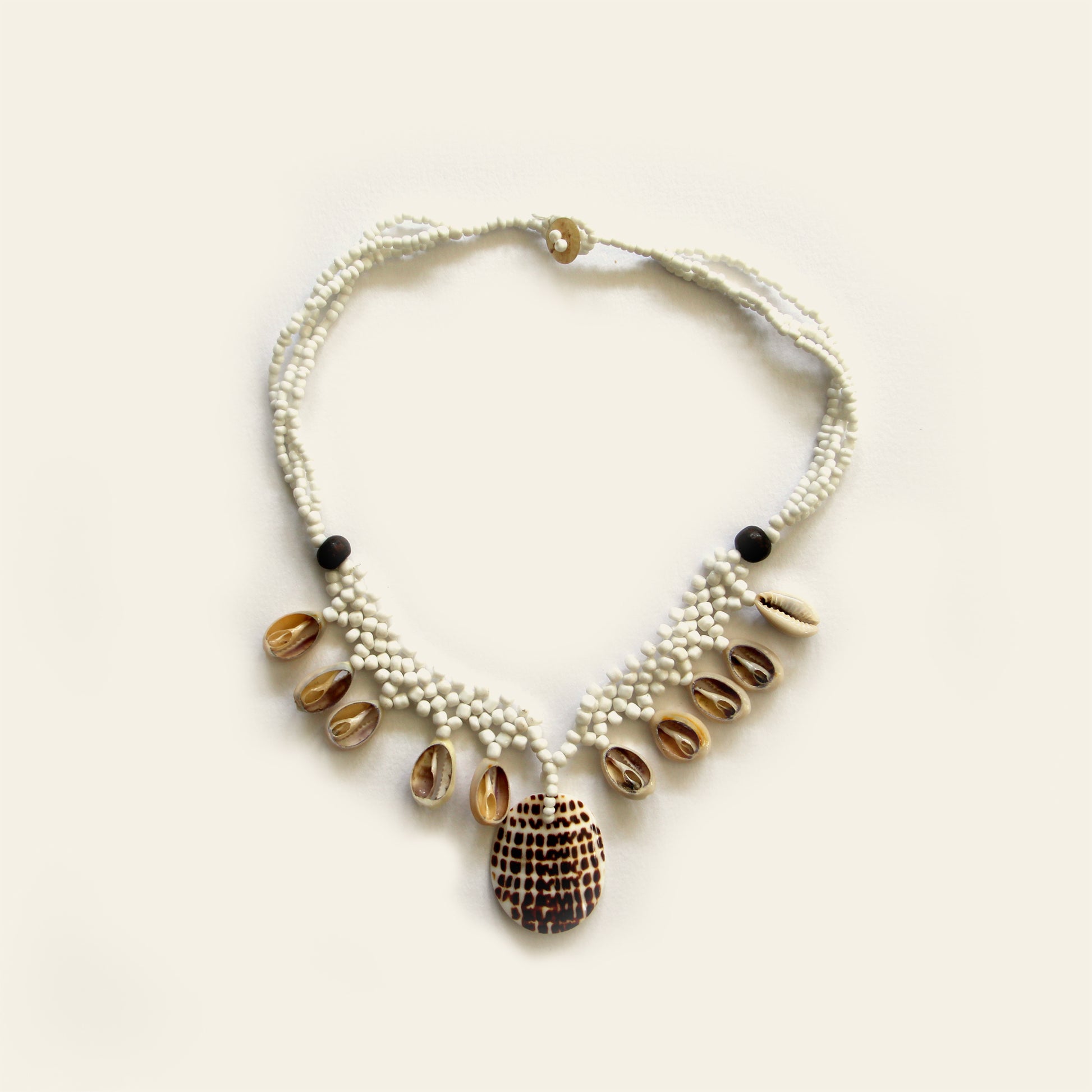 Handmade sand beaded necklace with dangling shells and a central spotted shell pendant – Nayabijou.