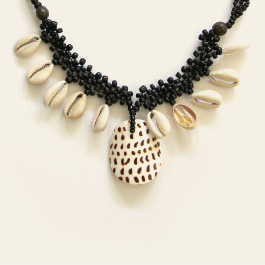 Closeup of handmade black beaded necklace with dangling shells and a central spotted shell pendant – Nayabijou.