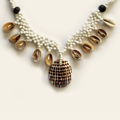 Closeup of handmade black beaded necklace with dangling shells and a central spotted shell pendant – Nayabijou.