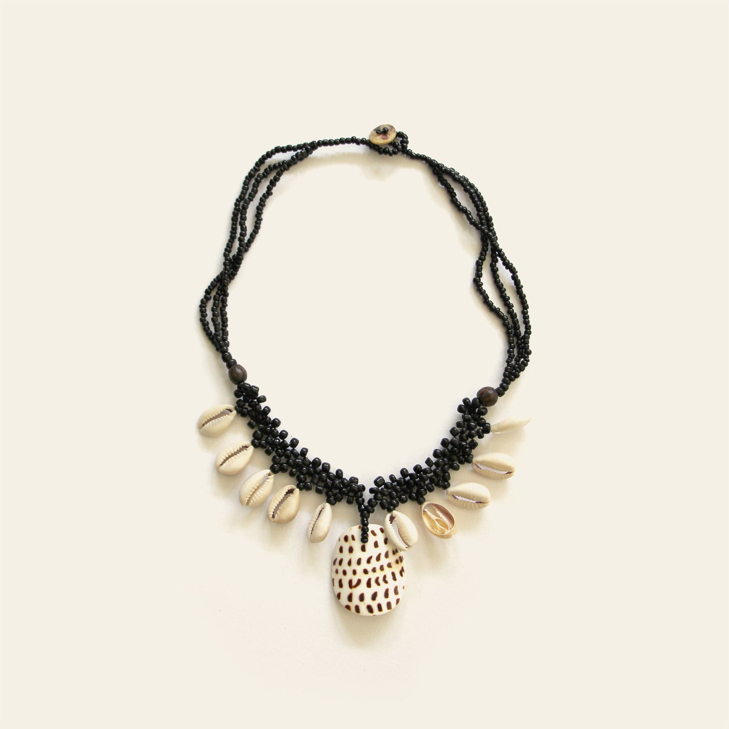 Handmade black beaded necklace with dangling shells and a central spotted shell pendant – Nayabijou.