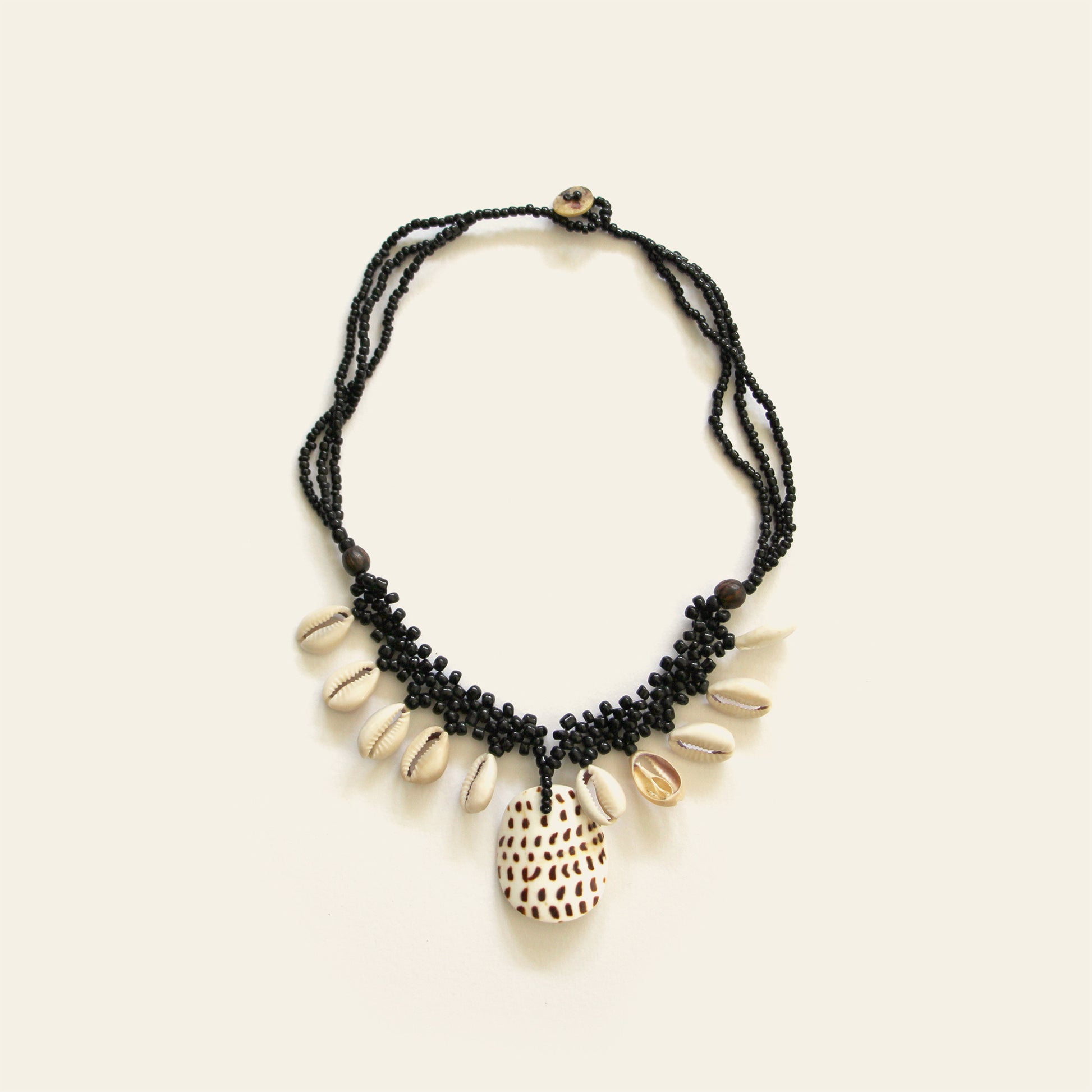 Handmade black beaded necklace with dangling shells and a central spotted shell pendant – Nayabijou.