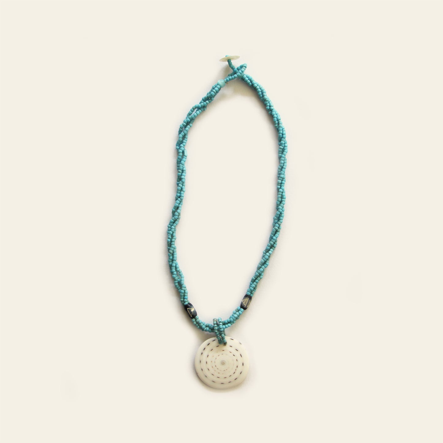 Handmade necklace with Turquoise seed beads, dark wooden accents, and a round spiral-patterned shell pendant — by Nayabijou.