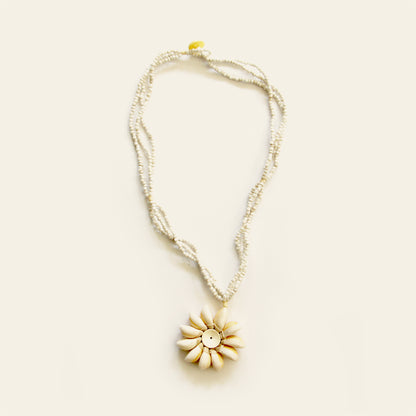 Handmade necklace with white seed bead strands and a central flower pendant made of natural shells arranged in a sunburst pattern — by Nayabijou.