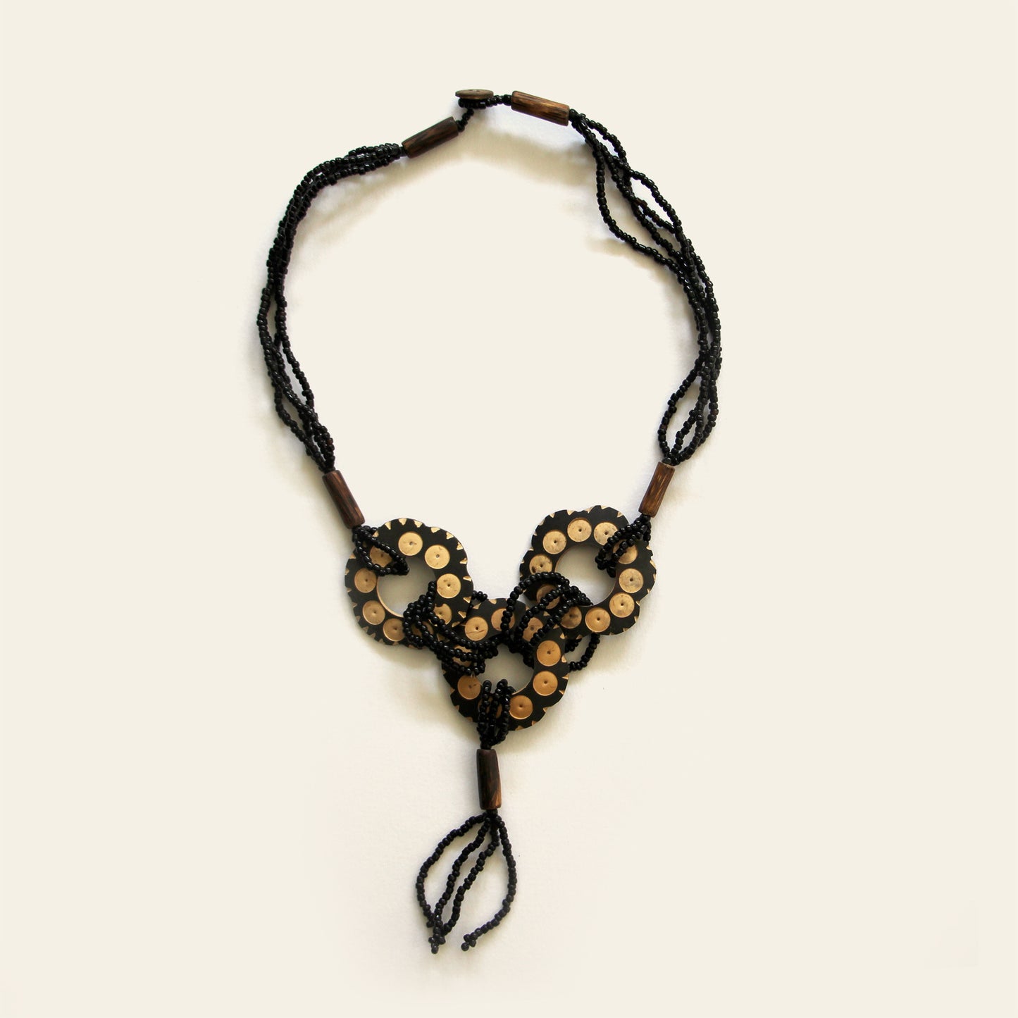 Handmade necklace featuring black seed beads and carved coconut shell loops linked together with beaded knots, finished with a tasseled drop — by Nayabijou.