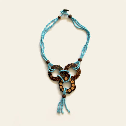 Handmade necklace featuring Turquoise seed beads and carved coconut shell loops linked together with beaded knots, finished with a tasseled drop — by Nayabijou.