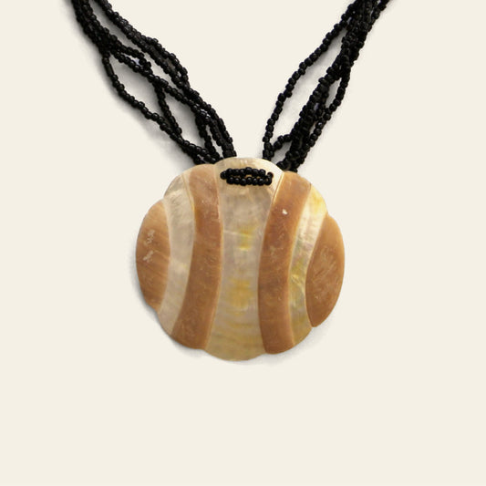 Closeup of handmade black beaded necklace with round Mother of Pearl pendant featuring wave-like beige patterns – Nayabijou.