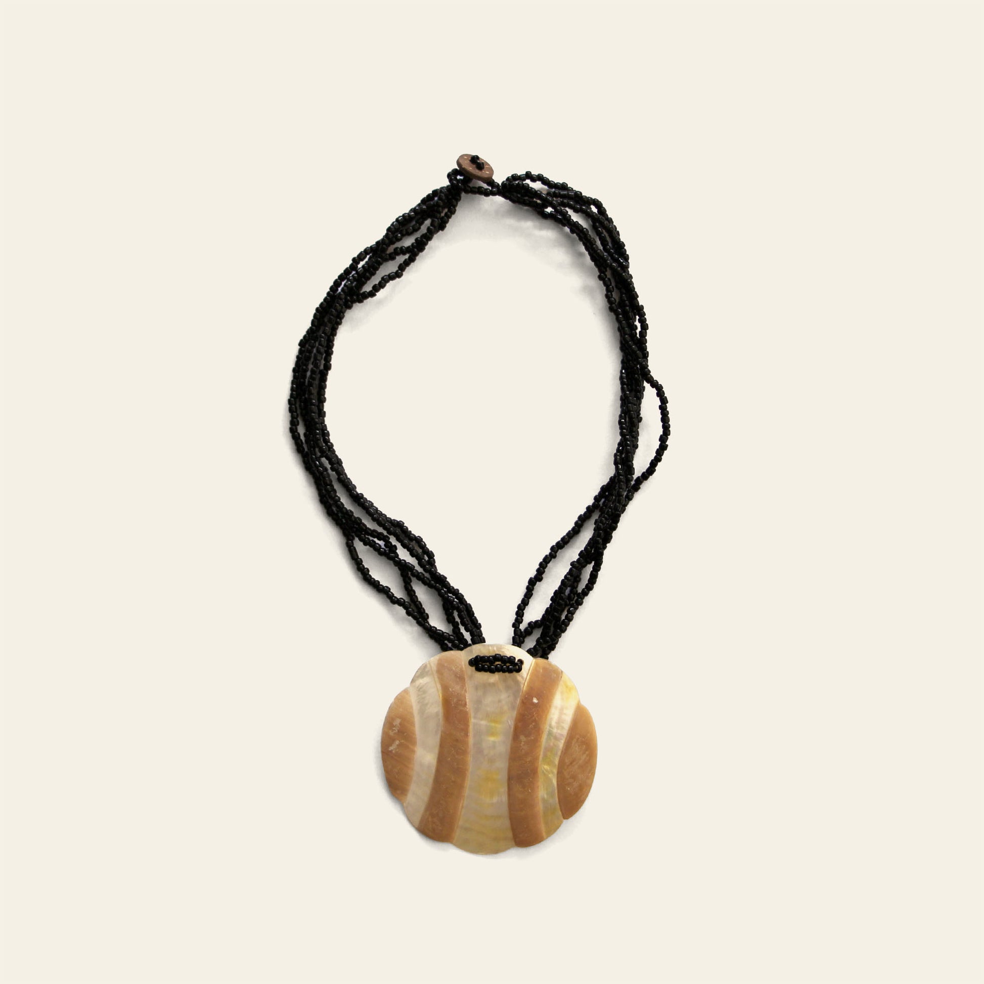 Handmade black beaded necklace with round Mother of Pearl pendant featuring wave-like beige patterns – Nayabijou.