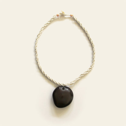 Handmade necklace with off-white seed beads and a smooth black wooden pendant, designed by Nayabijou.