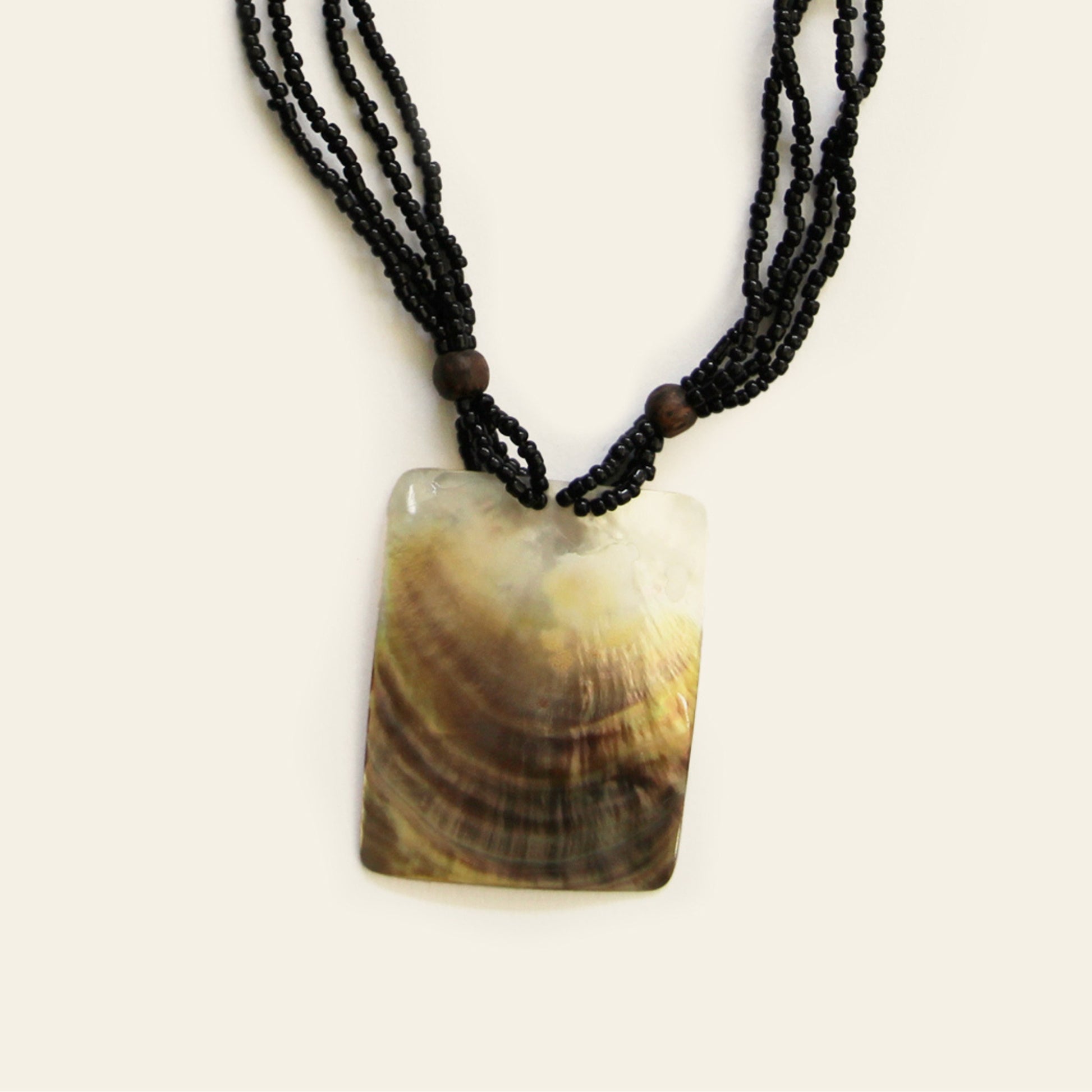 Closeup of rectangular mother-of-pearl pendant necklace with layered black seed beads – Nayabijou.