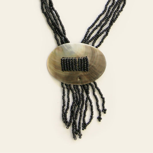 Close-up of oval shell pendant with threaded black seed beads and fringe strands – Nayabijou.