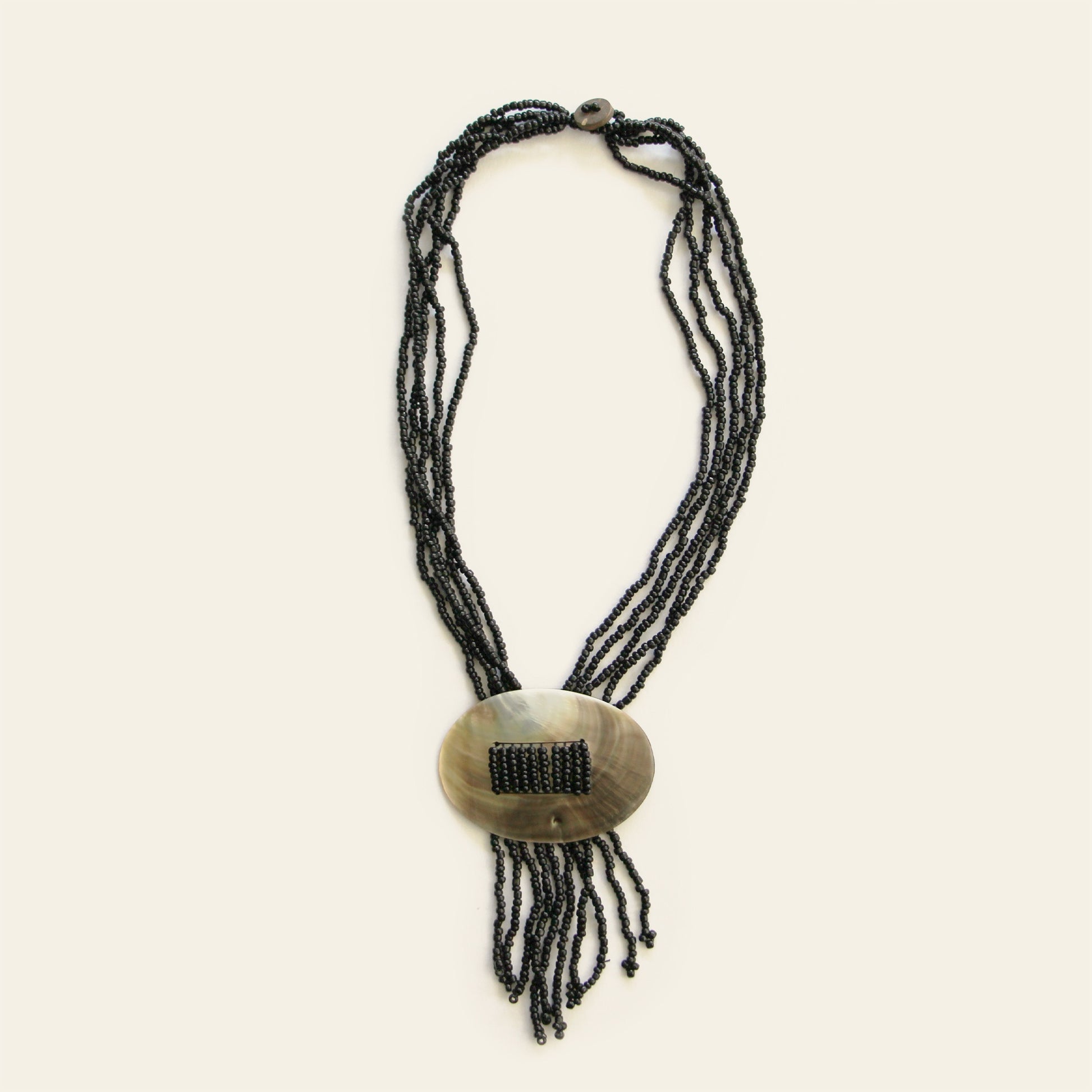 Full view of oval mother-of-pearl pendant necklace with black beaded strands and fringe – Nayabijou.