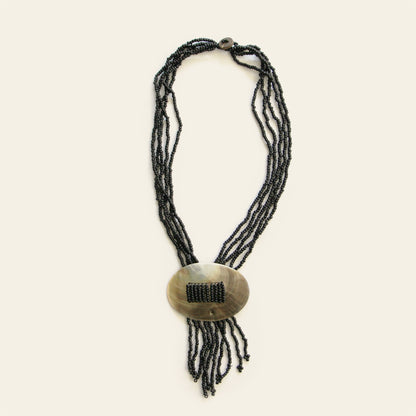 Full view of oval mother-of-pearl pendant necklace with black beaded strands and fringe – Nayabijou.