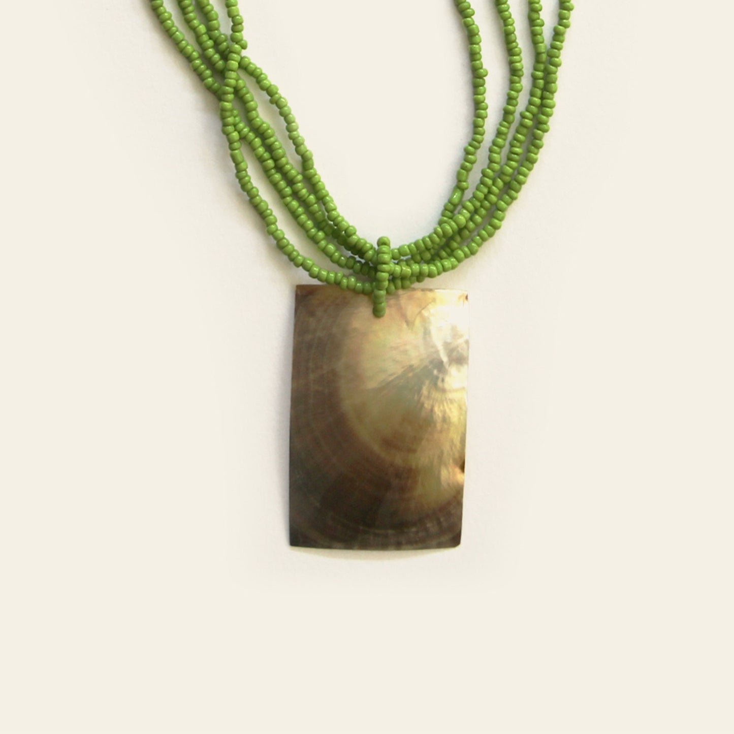 Closeup of rectangular mother-of-pearl pendant necklace with bright green seed beads – Nayabijou.