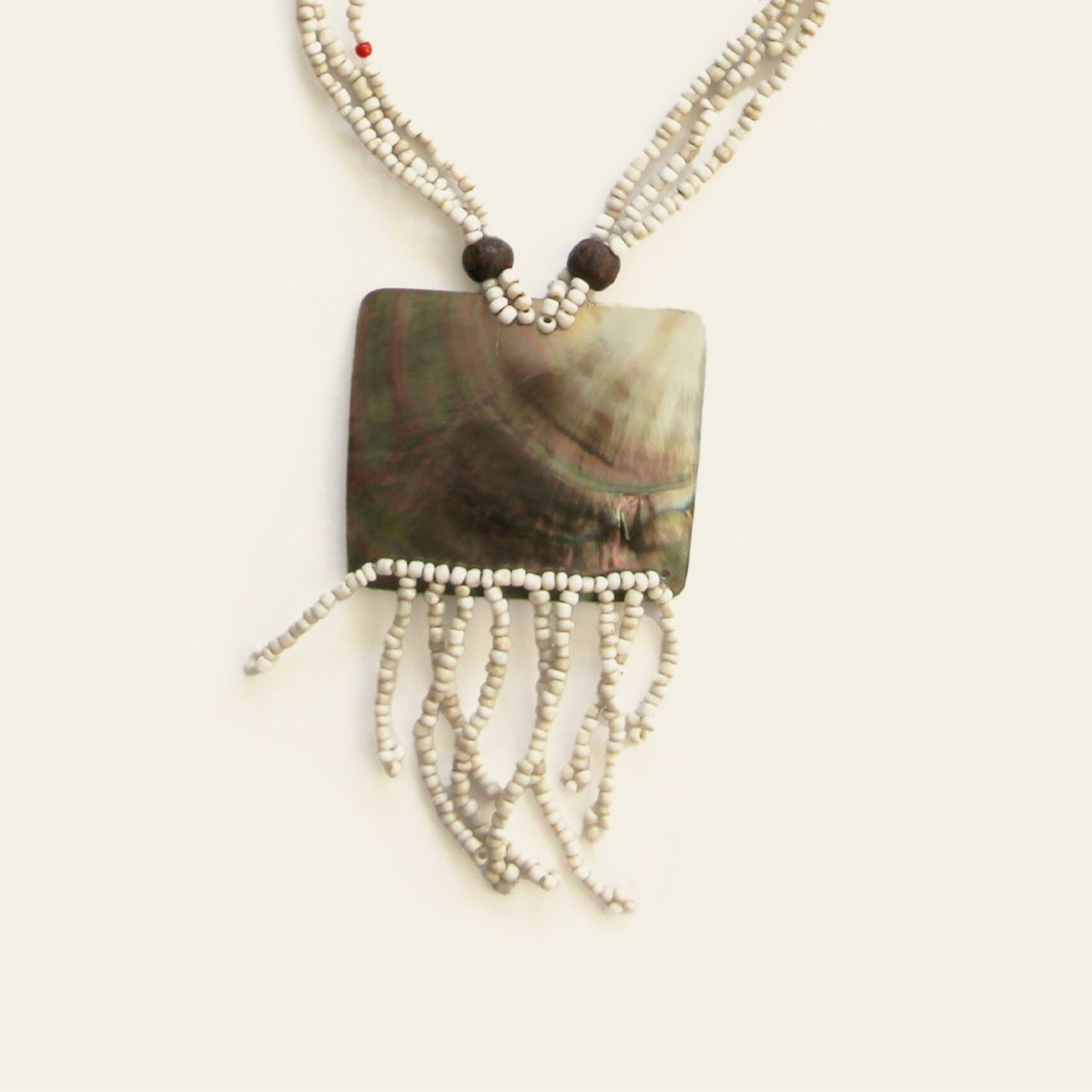 Close-up of rectangular shell pendant with ivory fringe and beaded strands – Nayabijou.