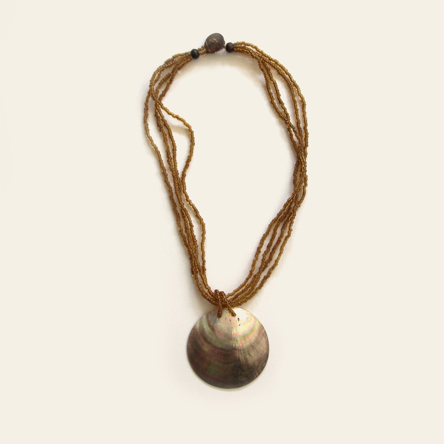 Handcrafted necklace with mother-of-pearl pendant and amber seed beads, full view